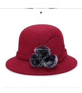 Dettaglio cappello cloche in lana bordeaux con decorazione a foglia e pompon in pelliccia
