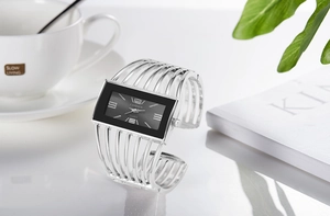 Close-up of silver hollow cuff watch for women with rectangular black dial on a magazine