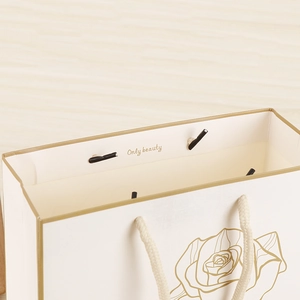 Close-up of white gift bag featuring golden rose pattern and Only Beauty inner printing
