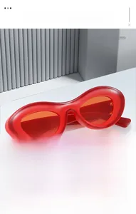 Close-up of trendy oval sunglasses with red thick frames and orange translucent lenses