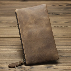 Close-up of brown crazy horse leather long wallet with zipper on rustic wood surface