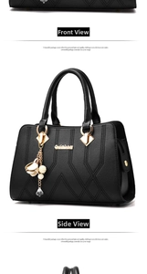 Detail of black quilted leather handbag with gold hardware and decorative charm pendant