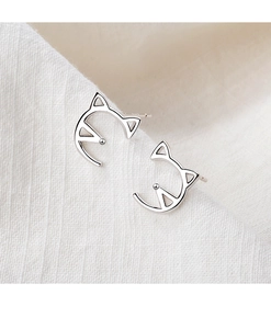 Macro shot of minimalist silver cat head stud earrings on textured white fabric