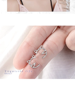 Macro shot of silver hollow cat ear studs on fingertips showing delicate craft