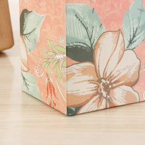 Gros plan détaillé d'une boîte cadeau à motif floral rose sur une table en bois clair