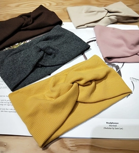 Flat lay of ribbed knit cross knot headbands in five earthy tones on a rustic table