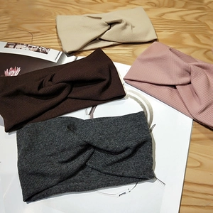 Flat lay view of four knitted twist headbands in beige, brown, pink, and grey colors