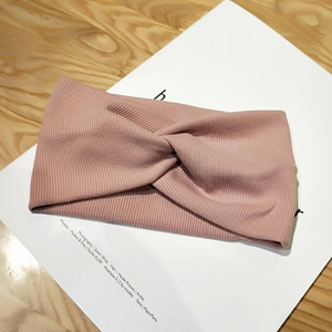 Close-up of pink knitted twist headband with ribbed fabric texture on wooden table