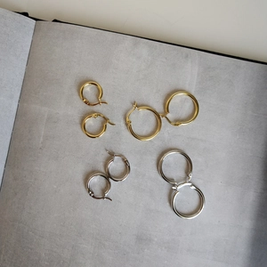 Three sizes of 925 sterling silver hoop earrings in gold and silver finishes on gray background