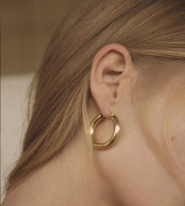 Close-up of model wearing polished gold hoop earrings in 925 sterling silver