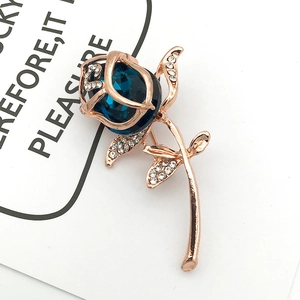 Macro detail of rose flower brooch with large deep blue crystal and zircon accents