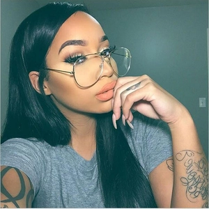 Close-up of a model wearing large gold metal pilot glasses frames with clear lenses