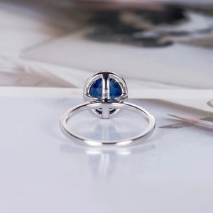 Exquisite silver ring featuring a large oval sapphire-blue stone with paved side diamonds