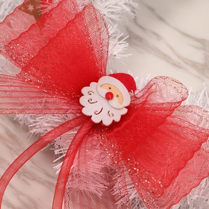 Christmas wreath with large red mesh bow and Santa Claus plush ornament on white tree