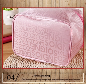 Close-up of pink makeup bag with SOIGNE letter patterns and metallic zipper detail