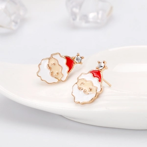 Macro shot of Santa Claus earrings with white rhinestones on a ceramic tray