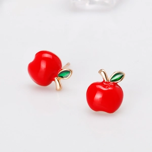 Detail of creative apple stud earrings with vibrant red enamel and golden finish