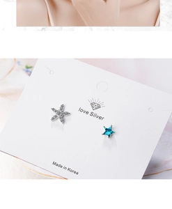 Macro shot of asymmetric silver stud earrings with blue star and rhinestone starfish detail