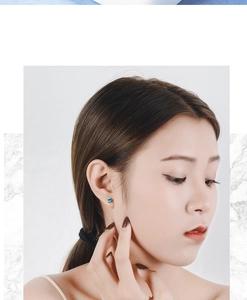 Close-up of model wearing blue star stud earrings with a minimalist asymmetric design