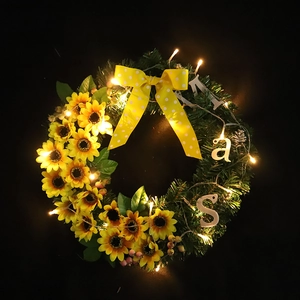 Sunflower Christmas wreath with green foliage, yellow polka dot bow, and warm LED lights