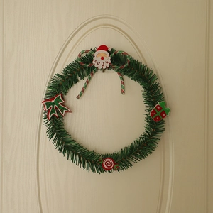 Green Christmas wreath with Santa Claus and red bows hanging on a white wooden door