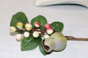 Detail of artificial Christmas berries with green leaves and a pink pomegranate decoration