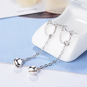 Elegant cat-shaped silver drop earrings with dainty bell pendants on a ceramic stand