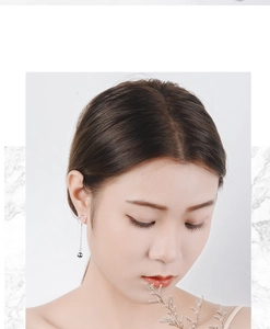 Close-up of cat-shaped silver dangling earrings with long tassels and beads on model
