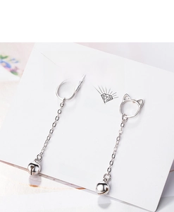 Close-up of silver cat earrings with long chain and small bell on a white display card