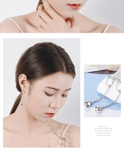 Detailed view of silver cat bell drop earrings showing elegant style on a female model