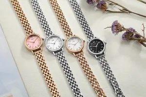 Detail of elegant NAIDU quartz watches with slim metal chain bracelets on white leather