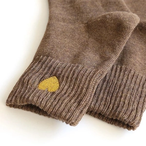 Close-up of brown knitted sock featuring a delicate gold heart embroidery on the ribbed cuff