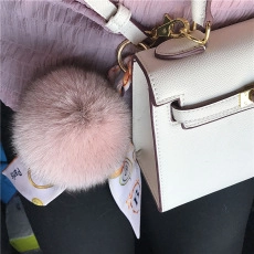 Pink mink fur pompom bag charm with Paris printed ribbon and golden metal clip on a handbag