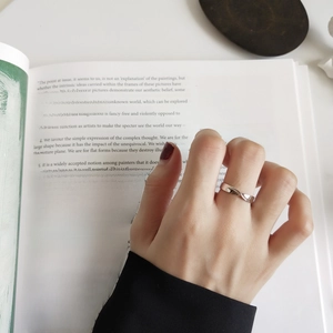 Detailed close-up of a silver twisted ring on finger with artistic book background