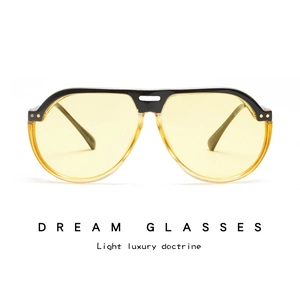 Detail of pilot-style sunglasses featuring black and yellow frames with yellow lenses
