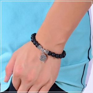 Close-up of black lava stone yoga bracelet with silver tree of life charm on wrist