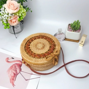 Detailed view of round straw woven crossbody bag with brown pattern and leather strap