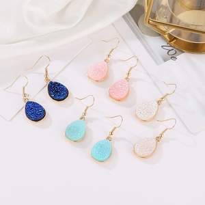 Close-up of bohemian colorful teardrop earrings in blue and pink with gold hooks
