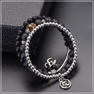 Detail of multi-layer lava stone bracelets with tiger eye bead and Om charm on black box