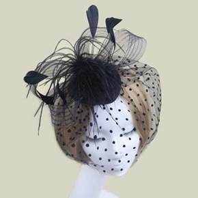 Detail of black feather fascinator with polka dot mesh veil on a white mannequin head
