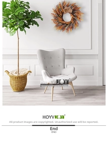 Detail of harvest wreath with grain ears hanging on a wall next to a grey armchair