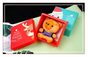 Detail of a Christmas gift box featuring a cute plush orange bear and festive holiday packaging