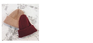 Detailed ribbed texture of khaki and burgundy knit beanies on white wall background