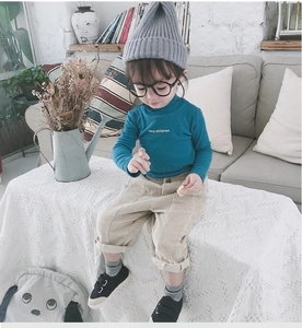 Detail view of peacock blue high-neck top and beige corduroy pants for children