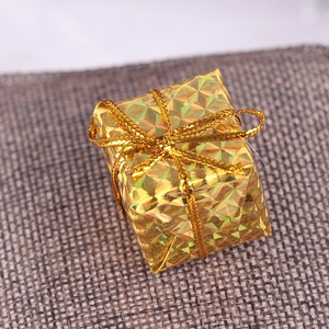 Macro shot of 2.5cm golden laser holographic mini gift box with bow on burlap