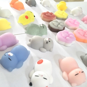 Assorted colorful animal and cat paw mochi squishy stress relief toys on white surface