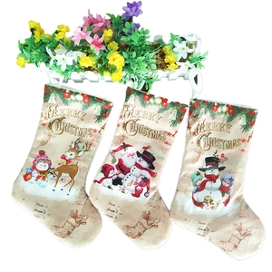 Three fabric Christmas stockings with Merry Christmas print hanging on white fence