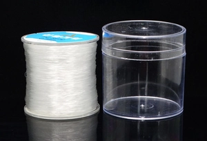 Close-up of clear elastic beading cord on white spool with matching plastic storage box