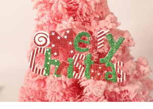 Gros plan d'une enseigne pailletée Merry Christmas sur un sapin de Noël rose