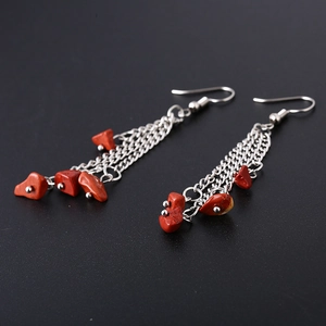 Detail of bohemian silver chain earrings featuring natural raw red crystal stone beads